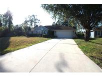 Charming single-story home with a well-manicured lawn and a long driveway leading to an attached two-car garage at 4749 Oakley Rd, North Port, FL 34288