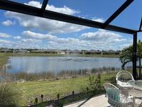 Relaxing screened-in lanai view features a serene lake with fountain and lush green landscaping at 7232 W Lenox Cir, Punta Gorda, FL 33950