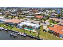 Aerial view of a luxury canal-front property with a boat dock and a sparkling swimming pool at 810 Napoli Ln, Punta Gorda, FL 33950