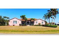 Charming single-story home with tile roof, beautiful lawn, and mature palm trees under a clear blue sky at 8233 Burwell Cir, Port Charlotte, FL 33981
