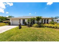 Charming single-story home featuring a lush green lawn, mature landscaping, and an attached one car garage at 11105 Pendleton Ave, Englewood, FL 34224