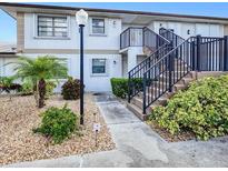 Well-maintained two-story condo building with lush landscaping and stairs leading to the upper units at 26485 Rampart Blvd # C1, Punta Gorda, FL 33983