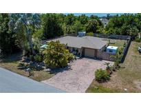 Charming single-story home with a brick-paved driveway and lush tropical landscaping, enclosed by a wooden fence at 3051 Chicory Ter, Punta Gorda, FL 33983
