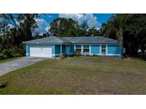 Charming single-story home featuring a blue exterior, well-maintained lawn, and attached two-car garage at 3175 Lakatos St, North Port, FL 34286