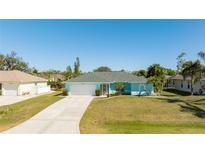 Charming single-story home featuring a light blue exterior, well-manicured lawn, and a spacious driveway at 4260 Kessler Ter, North Port, FL 34287