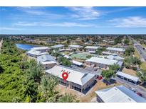 An aerial view of condo community featuring lush landscaping, lake, and nearby tennis courts at 9850 Fiddlers Green Cir # 130, Rotonda West, FL 33947