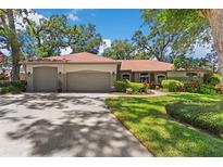Charming single-story home with a three-car garage, mature landscaping, and a well-manicured lawn at 1102 Hunt Club Ln, Valrico, FL 33594