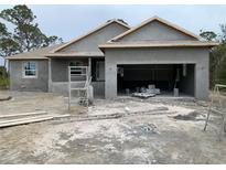 Under construction single-story house with open garage, light grey stucco, and visible materials at 135 Hardee Way, Rotonda West, FL 33947