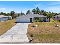 Charming single-story home with a well-maintained lawn, mature palm trees, and a concrete driveway at 18151 Cochran Blvd, Port Charlotte, FL 33948