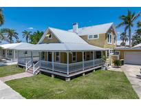 Charming two-story home featuring a wraparound porch, a metal roof, and a well-manicured lawn at 110 Gilchrist St, Punta Gorda, FL 33950