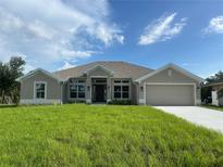 Charming single-story home with neutral paint, manicured lawn, and an attached two-car garage at 23245 Jules Ave, Port Charlotte, FL 33980