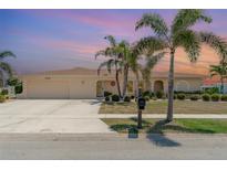 Charming single-story home featuring mature palm trees, a two-car garage, and a well-manicured lawn at 283 Fields Se Ter, Port Charlotte, FL 33952