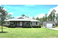 Charming single-story home with covered porch, green lawn and a detached garage or shed on a sunny day at 6405 Alan Blvd, Punta Gorda, FL 33982