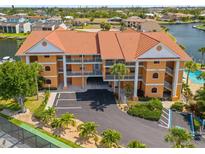 Well maintained condo building with a vibrant red-tile roof, lush landscaping, and plentiful parking at 1326 Wesley Dr # 132, Punta Gorda, FL 33950