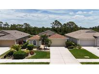 Charming single-story home features a well-manicured lawn, a two car garage, and mature landscaping at 1566 Scarlett Ave, North Port, FL 34289