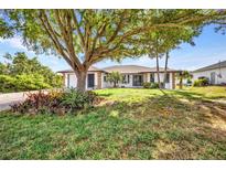 Charming single-story home featuring mature trees, lush landscaping, and a well-manicured lawn at 18753 Klingler Cir, Port Charlotte, FL 33948