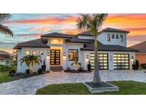 Stunning exterior of a modern home featuring a well-manicured lawn, palm trees, and decorative driveway pavers at sunset at 19 Sabal Dr, Punta Gorda, FL 33950