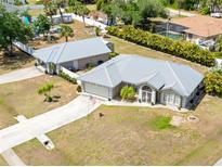 Inviting gray home featuring a metal roof, landscaped yard, and a long driveway leading to an attached garage at 2411 Atwater Dr, North Port, FL 34288