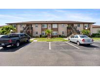 Condominium building with parking and landscaped grounds on a sunny day at 25100 Sandhill Blvd # R201, Punta Gorda, FL 33983