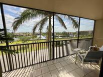 Relaxing screened balcony with seating and views of the palm trees and water at 25188 Marion Ave # F304, Punta Gorda, FL 33950