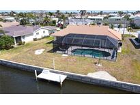 Aerial view of screened-in pool and dock in backyard on a waterfront property surrounded by mature landscaping at 425 Belvedere Ct, Punta Gorda, FL 33950
