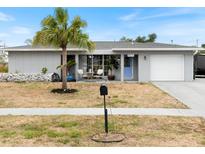 Charming single-story home with a well-manicured lawn, a light blue door, and an attached garage at 6531 Marius Rd, North Port, FL 34287