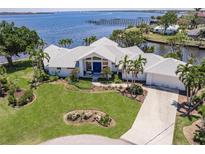 Stunning waterfront home with lush landscaping, mature palm trees, and scenic water views at 12439 Prather Ave, Port Charlotte, FL 33981