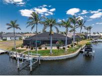 Waterfront home with screened lanai, pool, private boat dock and lift, surrounded by palm trees at 1255 Eider Ct, Punta Gorda, FL 33950