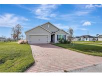 Charming single-story home with a well-manicured lawn and a brick driveway on a sunny day at 16031 Quinta Dr, Punta Gorda, FL 33955