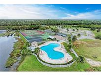 Aerial view features a unique pool design with tennis courts and palm trees in a well-maintained community at 175 Kings Hwy # 1114, Punta Gorda, FL 33983