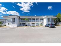 Well-maintained condo building with white facade, balconies, and ample parking under a blue sky at 22375 Edgewater Dr # 128, Port Charlotte, FL 33980