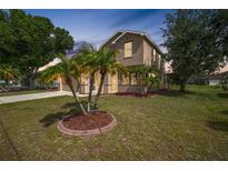 Inviting two-story home with a well-manicured lawn and palm tree landscaping at 26100 Paysandu Dr, Punta Gorda, FL 33983
