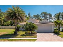 Charming single-story home featuring well-manicured lawn, palm trees, and a brick-paved driveway leading to a two-car garage at 4992 Brittain Way, North Port, FL 34287