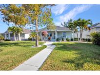 Charming single-story home boasts a manicured lawn, walkway, mature trees, and covered porch seating at 526 Allen St, Punta Gorda, FL 33950