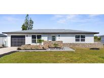 Charming one-story home featuring a decorative stone facade, well-manicured lawn, and a dark gray garage door at 124 Rotonda Cir, Rotonda West, FL 33947