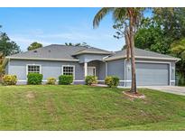 Charming single-story home with a well-manicured lawn, gray exterior, and attached two-car garage at 1275 Huntington St, North Port, FL 34288