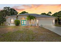Well-maintained home, features a charming front yard with palm trees, lush green lawn, and a two-car garage at 1313 Wise Dr, North Port, FL 34286