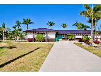 Single story home with well-manicured front lawn, palm trees, and a concrete driveway at 148 Peckham St Se, Port Charlotte, FL 33952