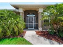 Inviting front entrance with decorative pillars and well-manicured landscaping featuring lush palms at 2288 Prague Ln, Punta Gorda, FL 33983