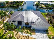 Aerial view of a waterfront home with a metal roof, lush landscaping, and boat dock access to a canal at 3520 Caya Largo Ct, Punta Gorda, FL 33950