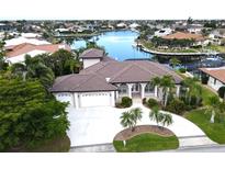 Stunning waterfront home featuring a circular driveway, a three-car garage, and lush landscaping at 3787 Whippoorwill Ct, Punta Gorda, FL 33950