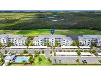 Beautiful aerial view of the complex with parking, pool, and golf course and wetlands in the background at 14061 Heritage Landing Blvd # 445, Punta Gorda, FL 33955