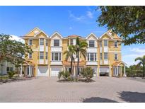 Beautifully landscaped yellow townhouse with three stories, garages, and a brick driveway at 1410 Park Beach Cir # 113, Punta Gorda, FL 33950