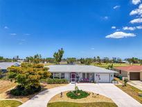 Charming single-story home with a circular driveway and well-maintained landscaping with golf course in the background at 142 Rotonda Cir, Rotonda West, FL 33947