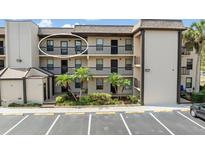 Exterior view of condo building with tropical landscaping, parking, and private balconies for each unit at 1999 Kings Hwy # 24C, Punta Gorda, FL 33980