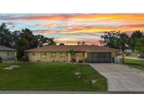Charming home boasts a well-maintained lawn and a neutral color scheme under a colorful sunset sky at 20355 Mount Prospect Ave, Port Charlotte, FL 33952