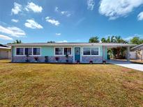 Charming single story home featuring a quaint carport, cheerful exterior color scheme, and low maintenance landscaping at 20407 Albury Dr, Port Charlotte, FL 33952