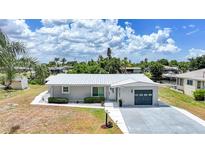 Beautiful one-story home featuring a manicured lawn, grey exterior, and a pristine white metal roof at 27385 Voyageur Dr, Punta Gorda, FL 33983