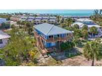 Stunning elevated beach house with wood decks, lush landscaping, and a metal roof with ocean view at 9390 Little Gasparilla Island, Placida, FL 33946