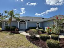 Charming home featuring manicured landscaping, healthy green lawn, and a beautiful walkway leading to the front door at 1025 Boundary Blvd, Rotonda West, FL 33947